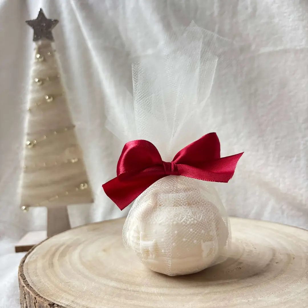 Świeca sojowa w kształcie bombki, ujęcie z boku w świątecznej aranżacji.