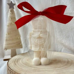 Świeca sojowa dziadek do orzechów w tiulowym woreczku z czerwoną wstążką.