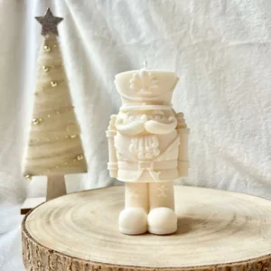 Świeca sojowa w kształcie dziadka do orzechów ustawiona na drewnianym krążku.