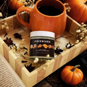 Świeca sojowa Jesieniara o zapachu słonego karmelu w jesiennej aranżacji z kubkiem herbaty i dyniami.