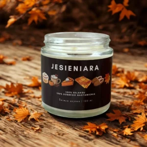 Świeca sojowa Jesieniara o zapachu słonego karmelu na drewnianym tle wśród jesiennych liści.
