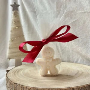 Świeca sojowa pierniczek w tiulowym woreczku z kokardą, w świątecznej scenerii.